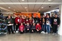 Employees wearing Christmas jumpers by the tree.